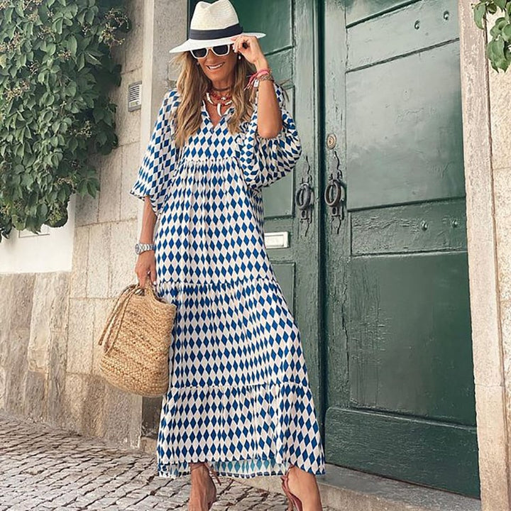 Woman posing in a patterned long dress with relaxed flowing fit against a plain backdrop.