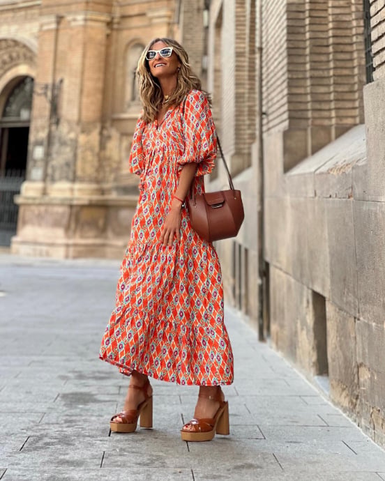 Woman wearing a bohemian style maxi dress with geometric pattern and puff sleeves.