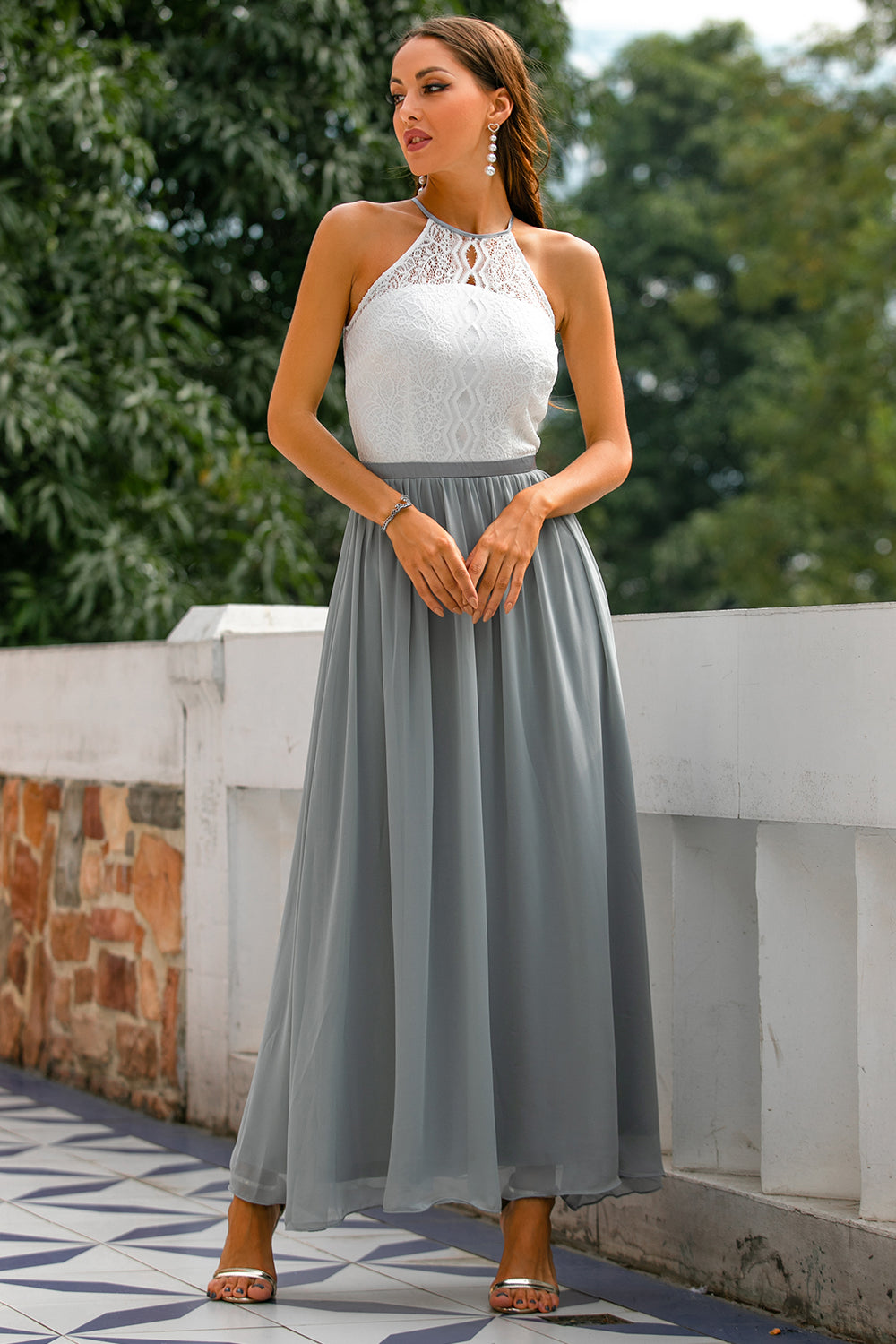 Female model posing in long formal dress with nature background.