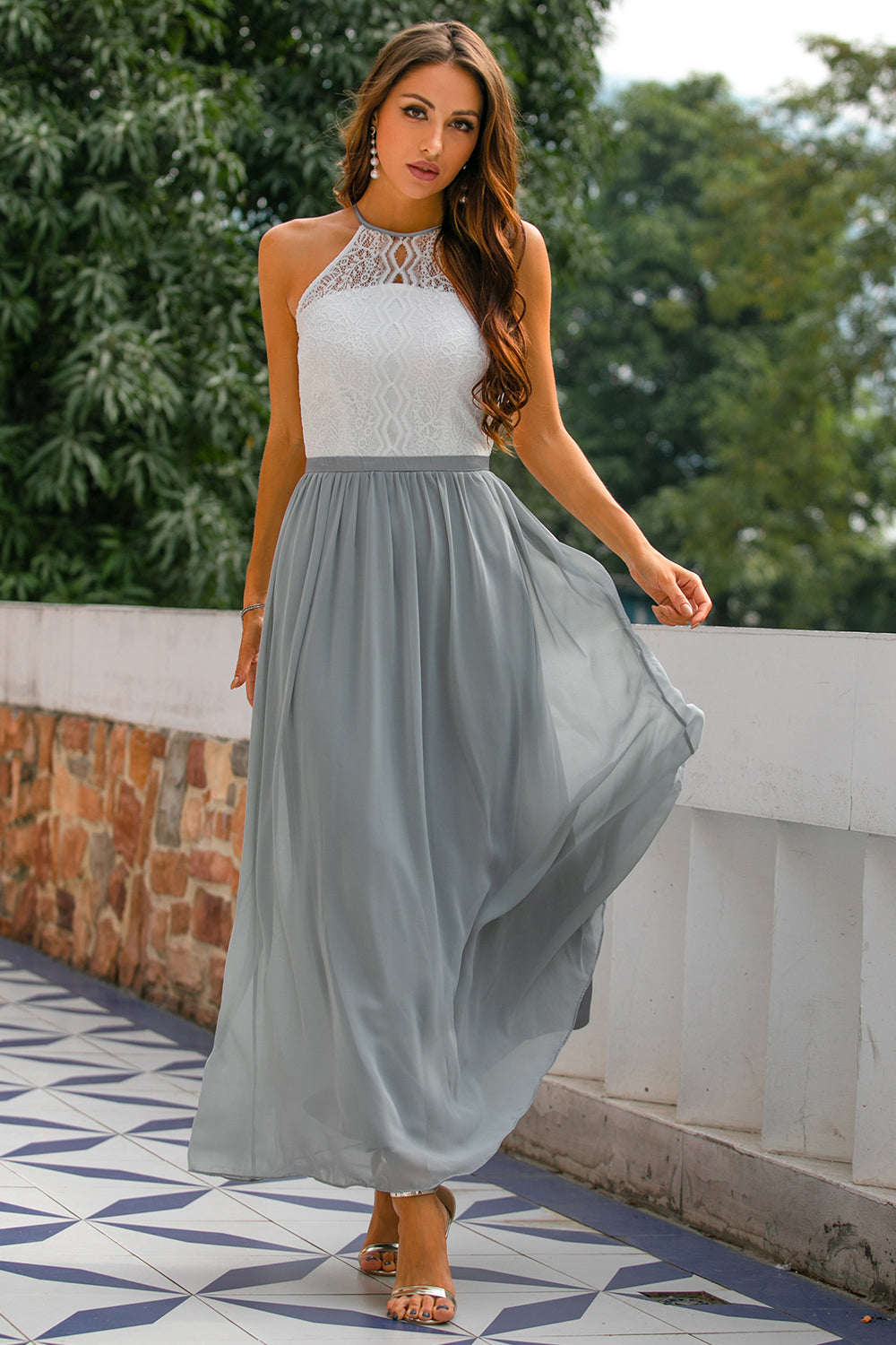 Woman wearing elegant halter maxi dress in terrace garden setting.