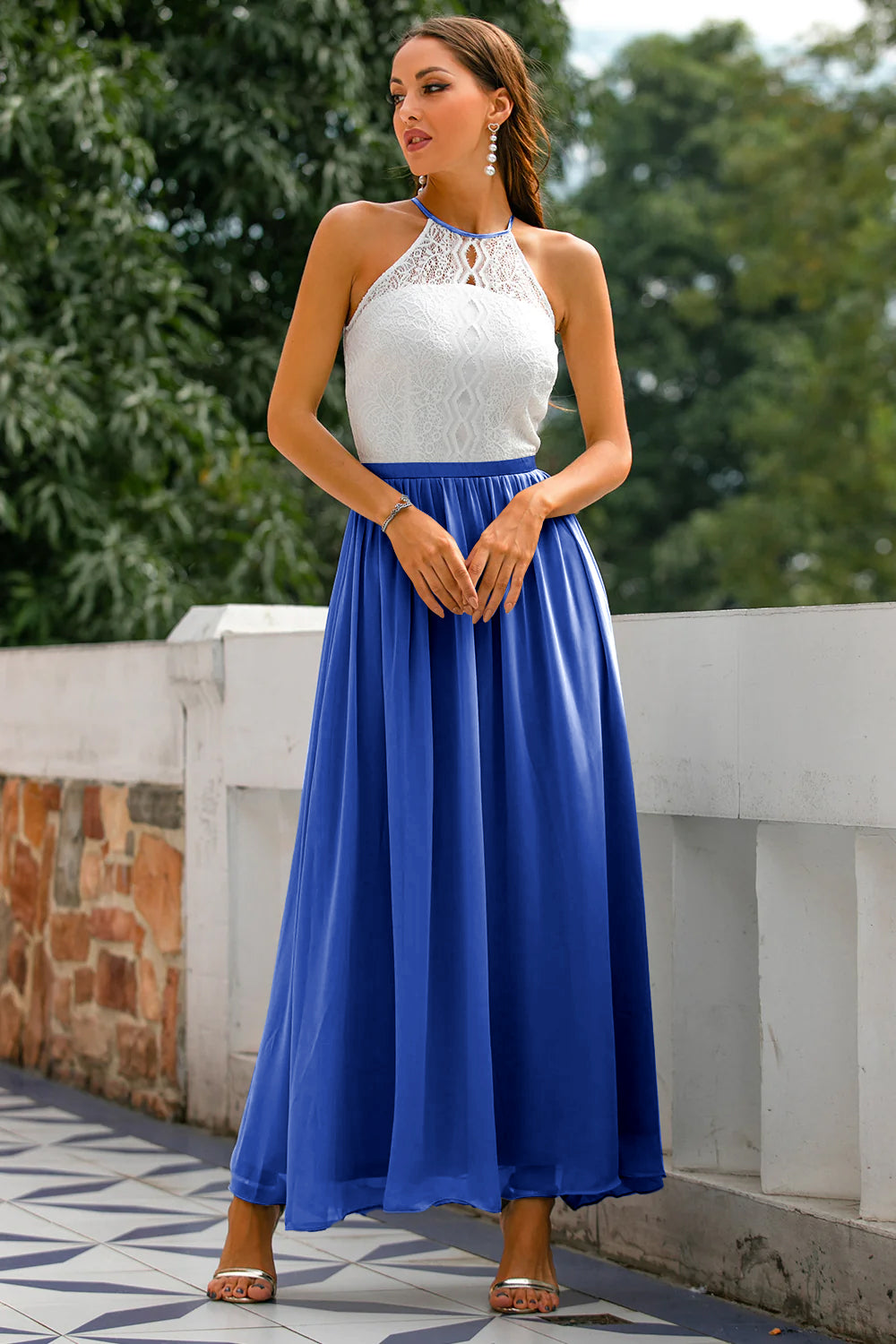 Female model posing gracefully in wedding guest outfit outdoors.