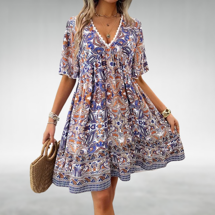 Woman modeling a paisley print mini dress with short sleeves on a plain background