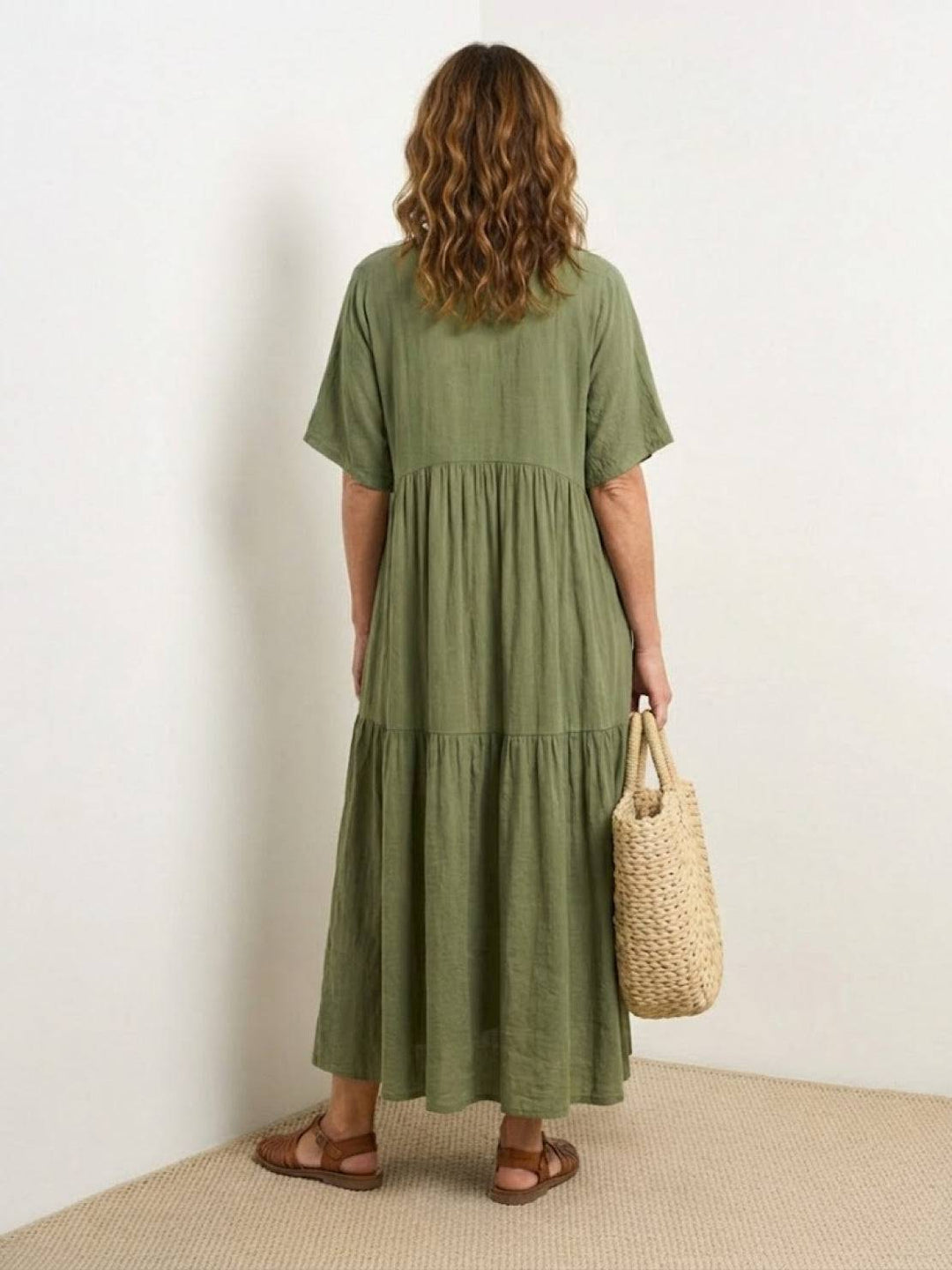 Female wearing a boho-inspired maxi dress with layered skirt detailing on a plain background.