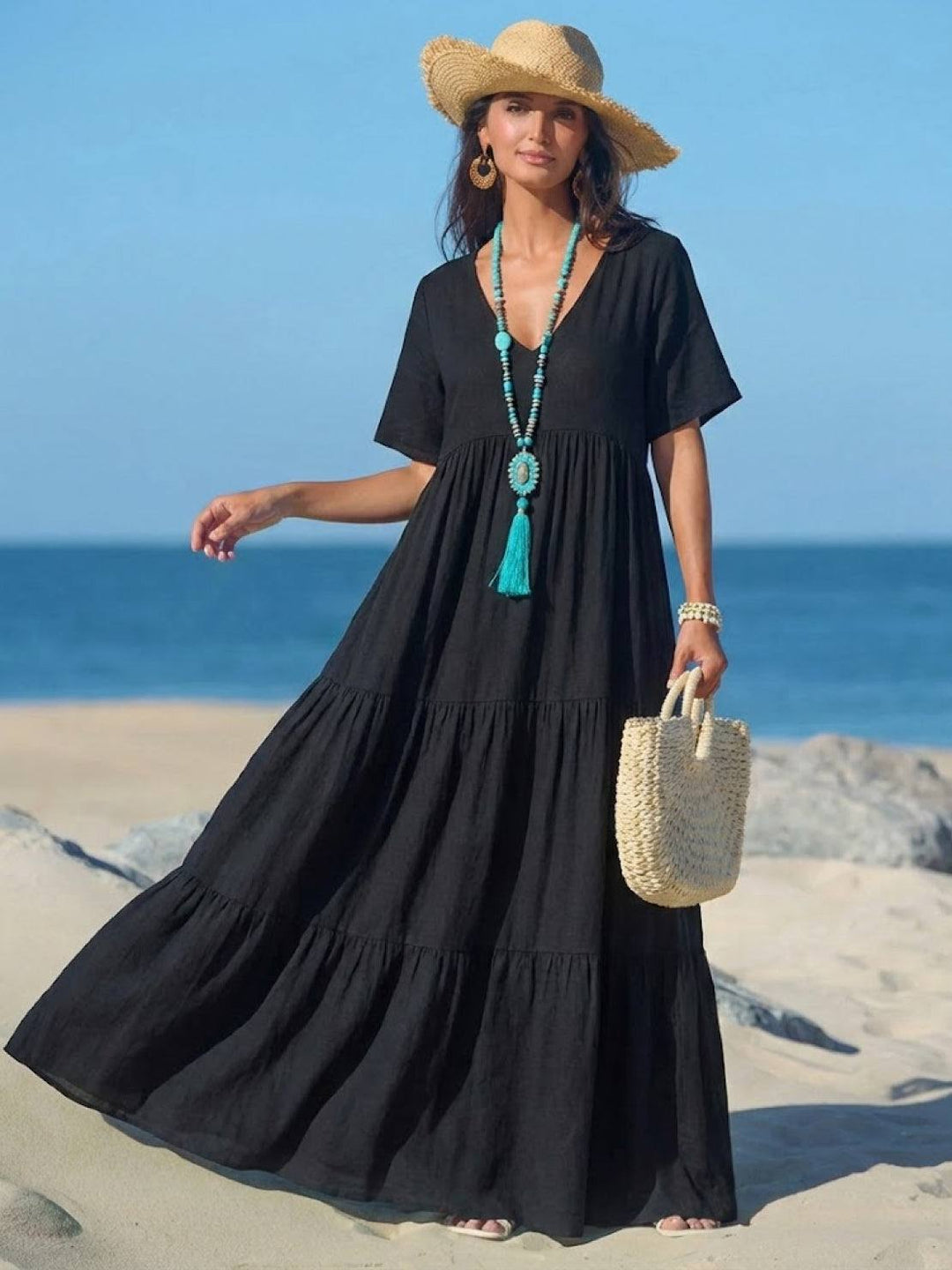 Model posing in a floor-length tiered dress with an airy silhouette on a plain background.