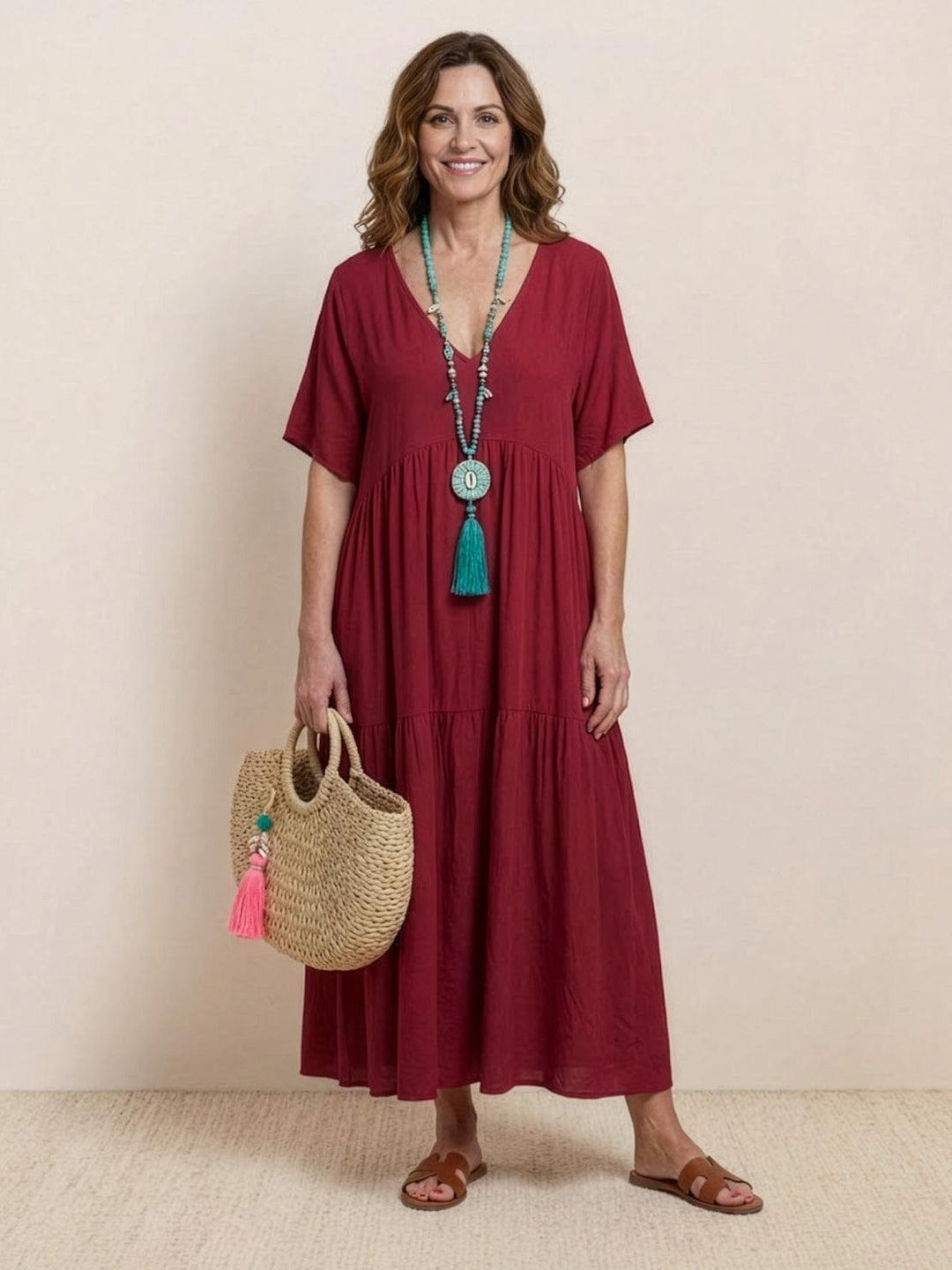 Female model wearing a flowing long dress with layered skirt details against a plain backdrop.