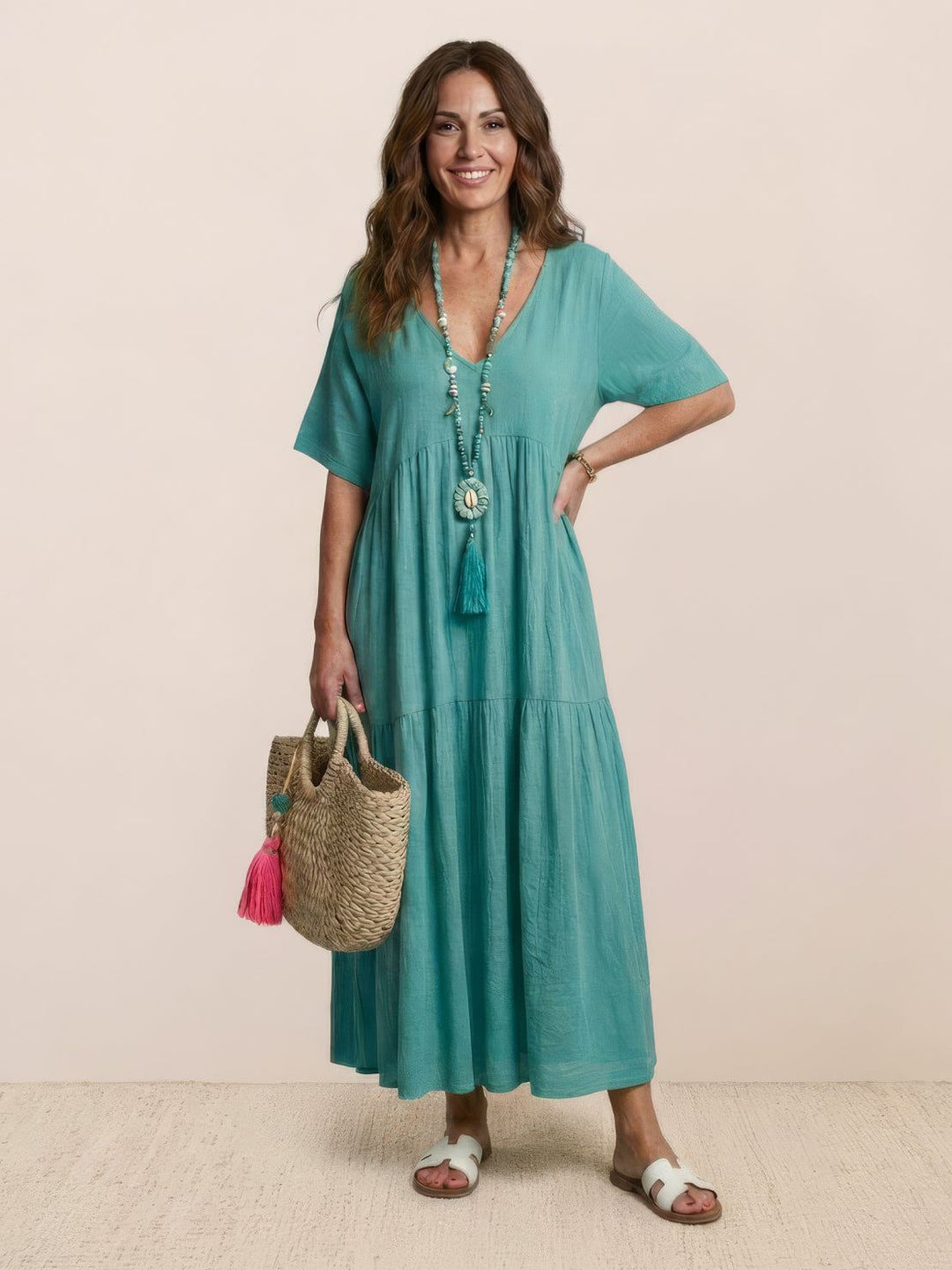 Female in a breezy terracotta long dress with flowing movement on a plain background.