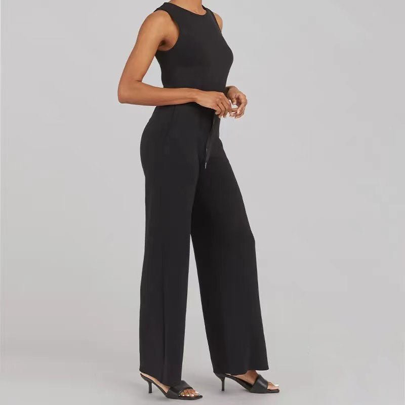 Woman wearing a refined one-piece jumpsuit with a graceful neckline on a plain background.