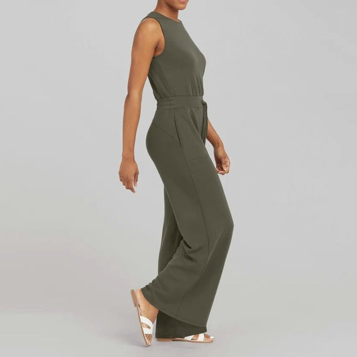 Female model wearing a polished jumpsuit with a graceful neckline on a plain background.
