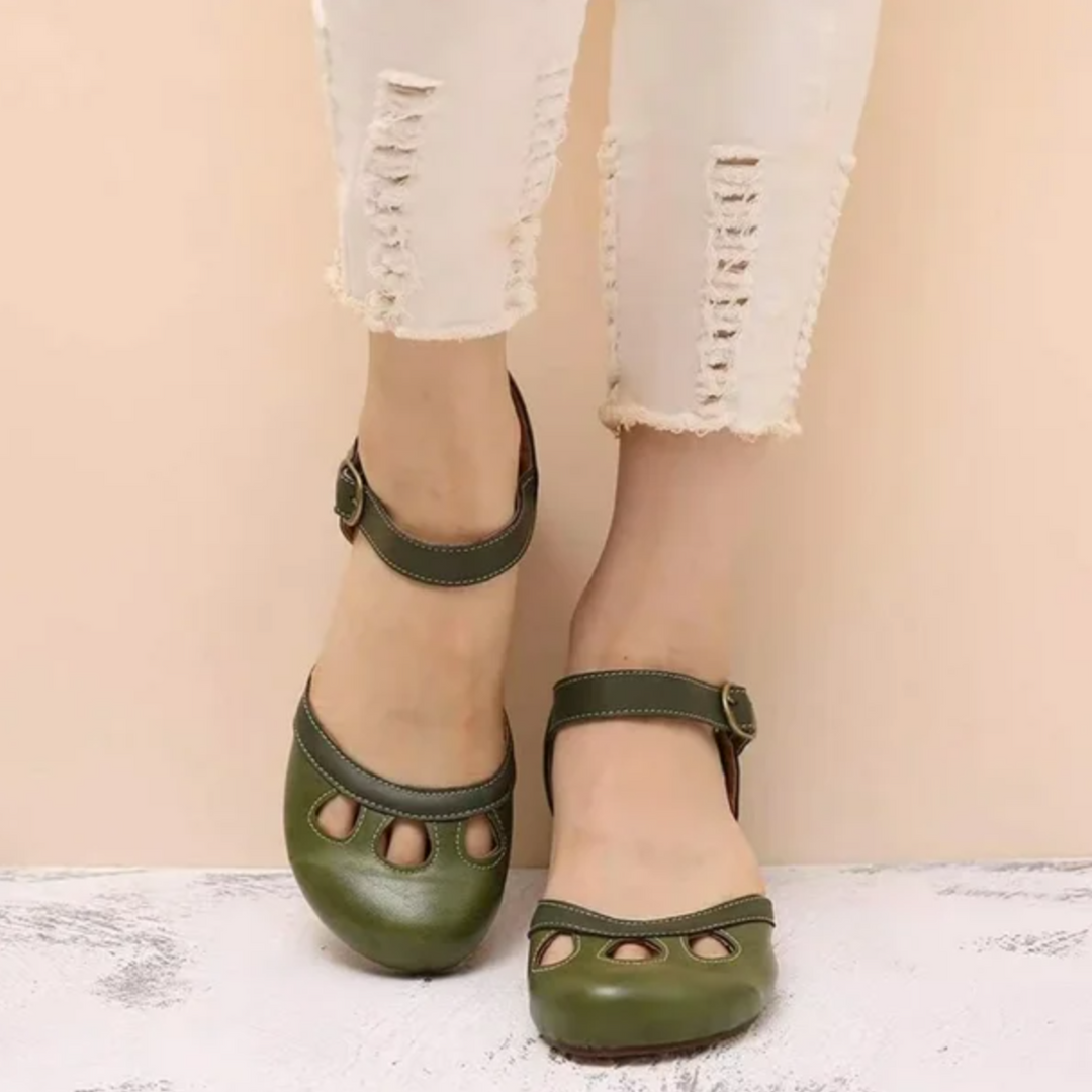 Foot wearing orthopedic women’s sandal on a plain background.