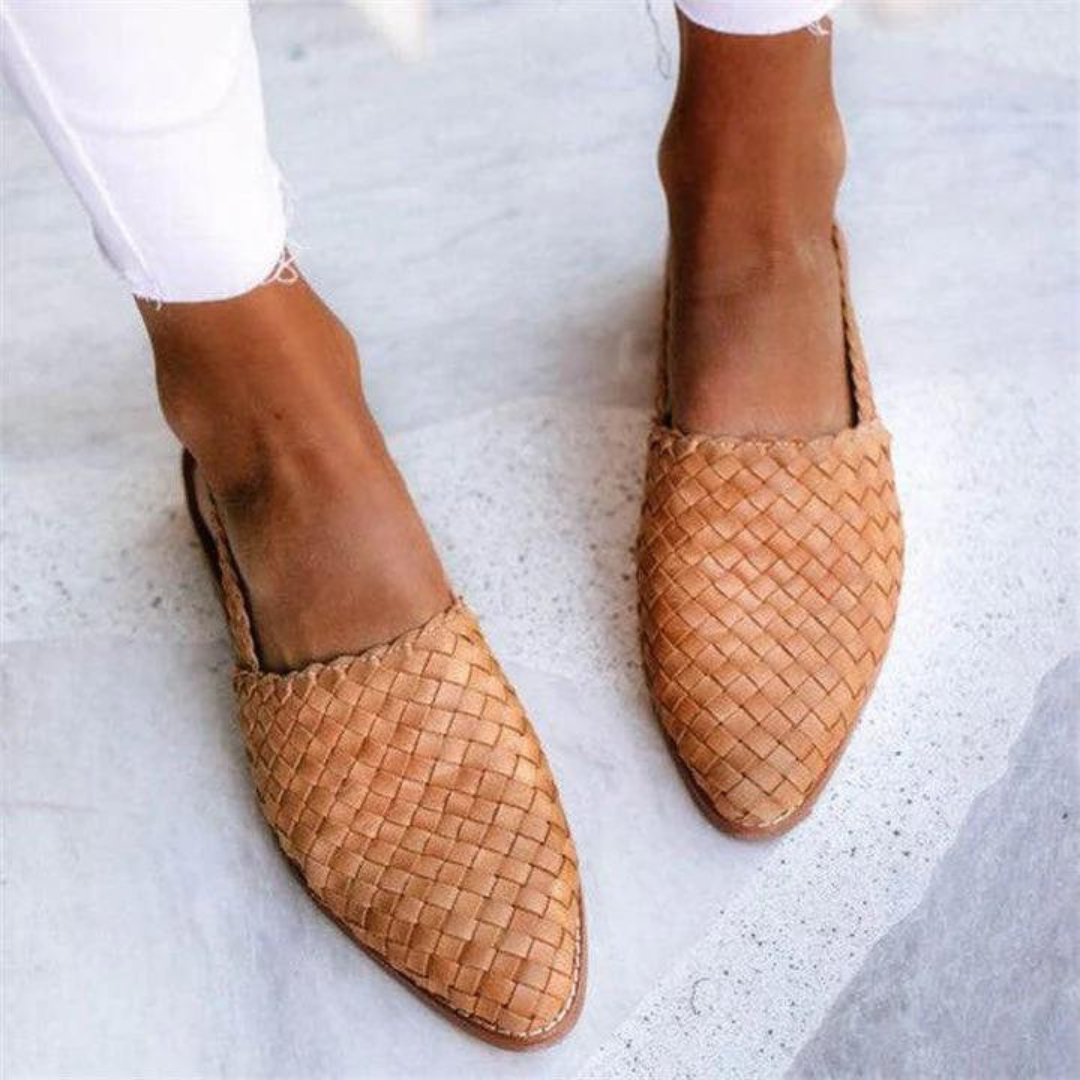  Woman showcasing textured woven flat loafers with a slip-on design on a plain background.