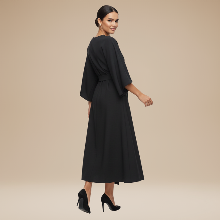 Model wearing a refined wrap midi dress with draped waist styling on a plain background.
