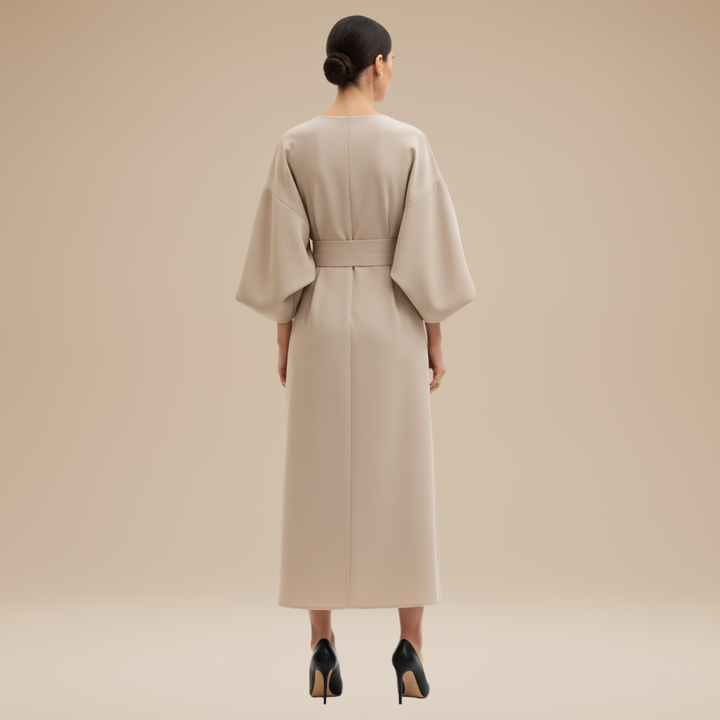 Woman wearing a graceful wrap dress with wide sleeves and cinched waist on a plain background.