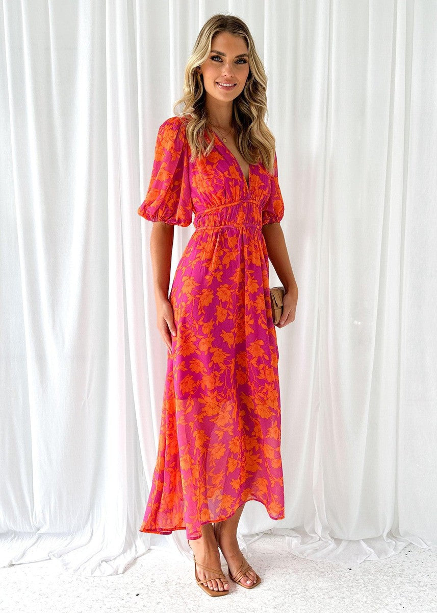 Woman in printed maxi dress on curtain background, front angle.