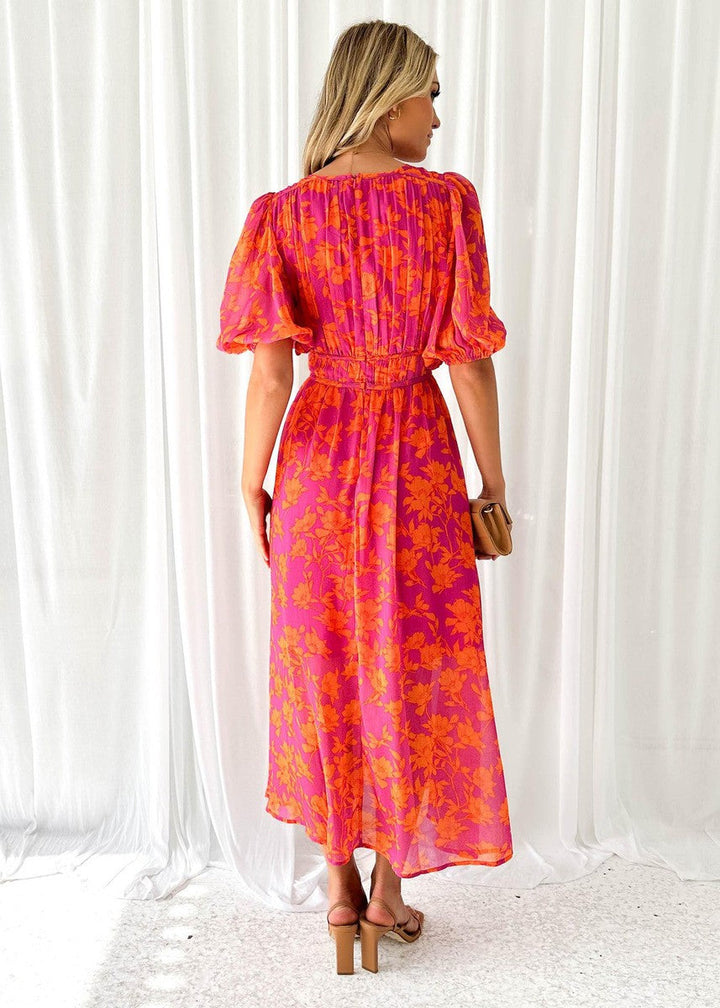 Woman wearing flowy occasion dress on curtain background, back angle.
