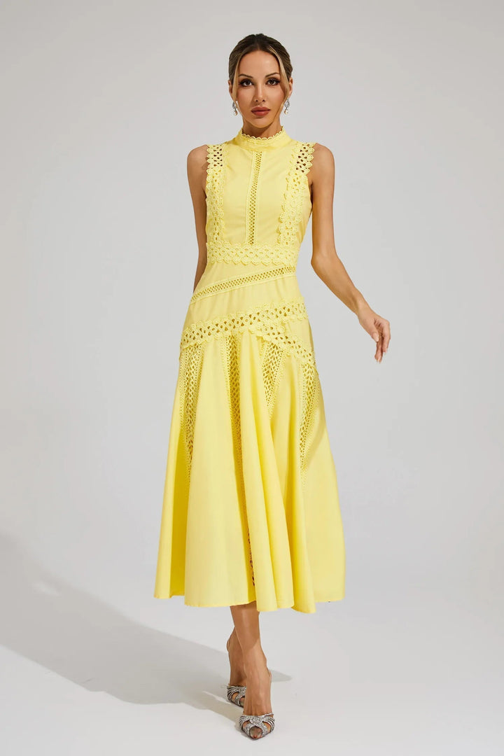 Female wearing a sleeveless midi dress with decorative detailing and a flared skirt against a plain background.