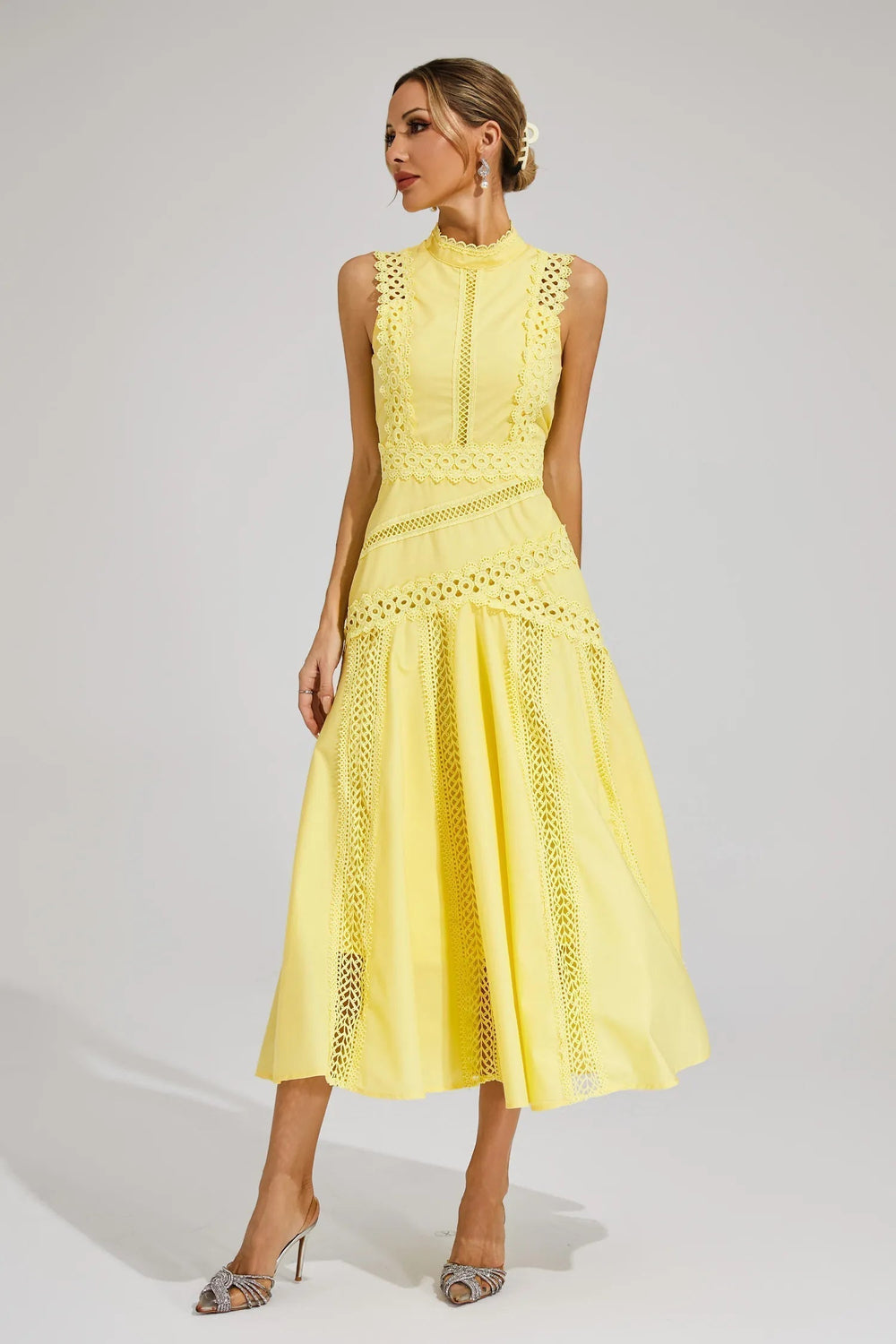 Woman modeling a sleeveless midi dress featuring an elegant fitted bodice and flowing silhouette on a plain background.