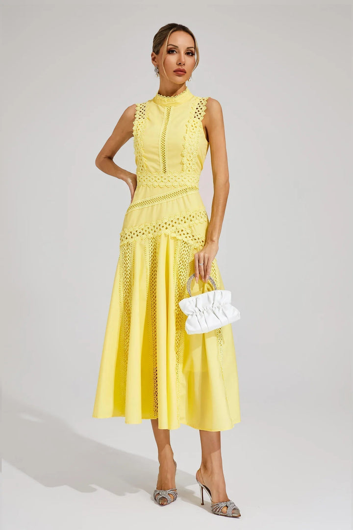 Woman wearing a midi dress with decorative details and a graceful flared hem against a plain background.