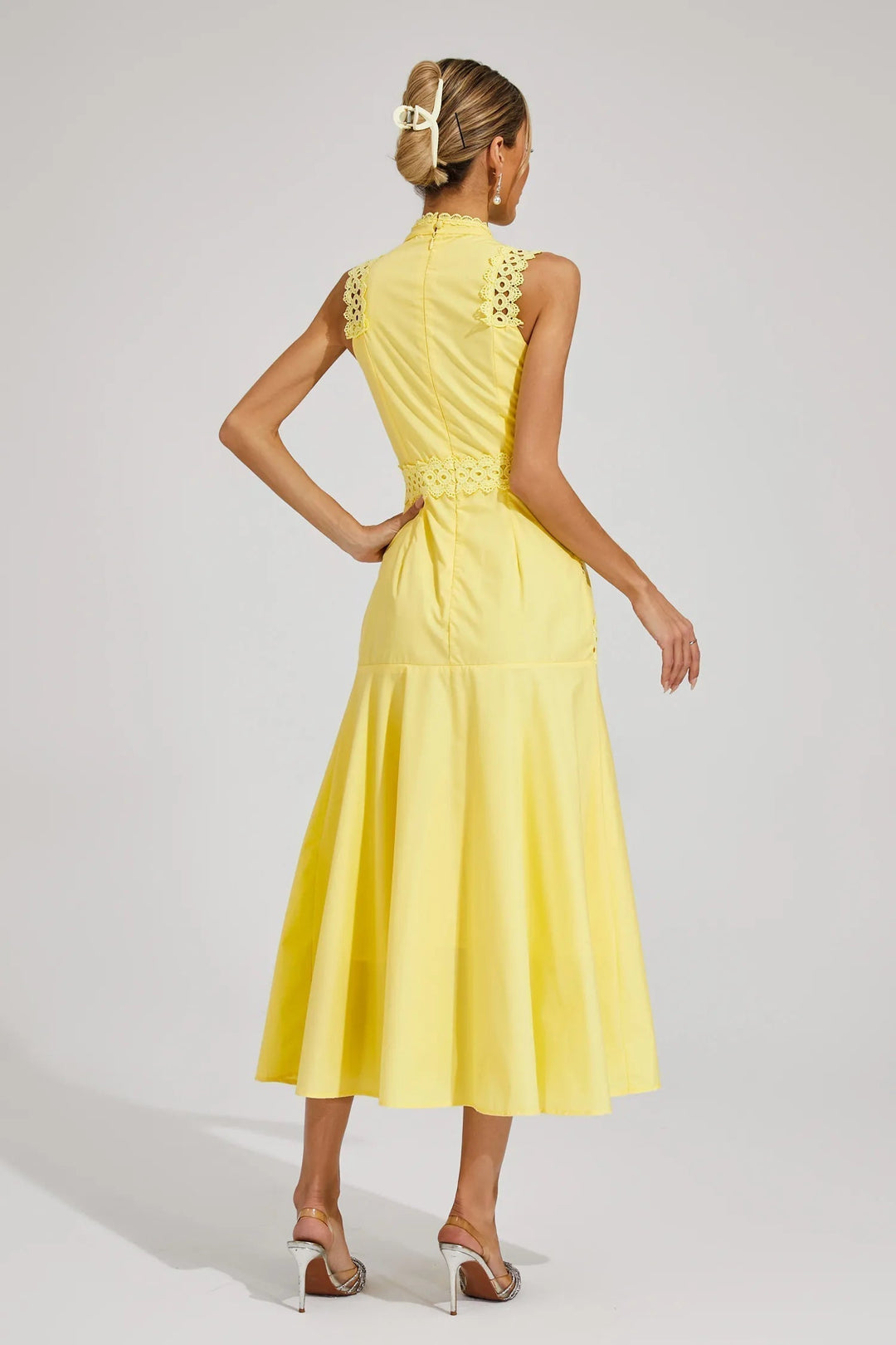 Female in a structured sleeveless midi dress with refined accents and a softly flared skirt on a plain background.