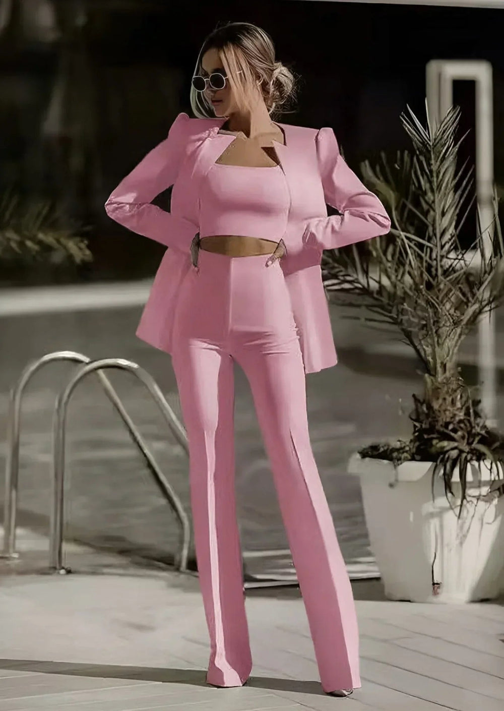 Woman in a two piece pant suit set with long sleeve blazer on a plain background..