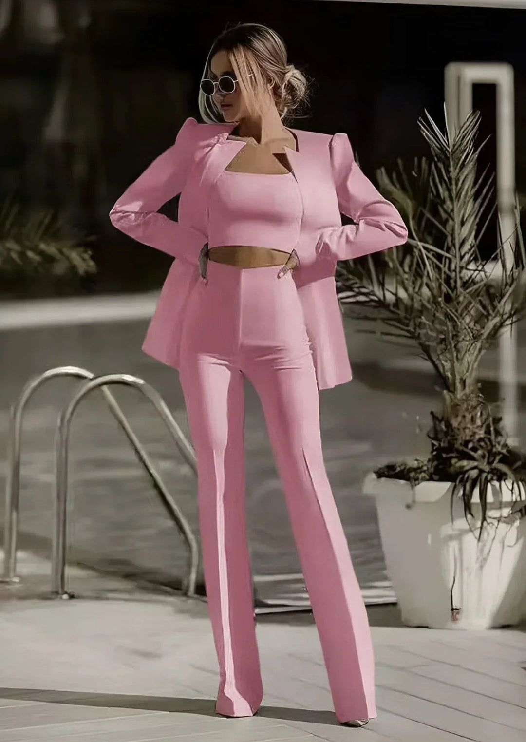 Woman in a two piece pant suit set with long sleeve blazer on a plain background..