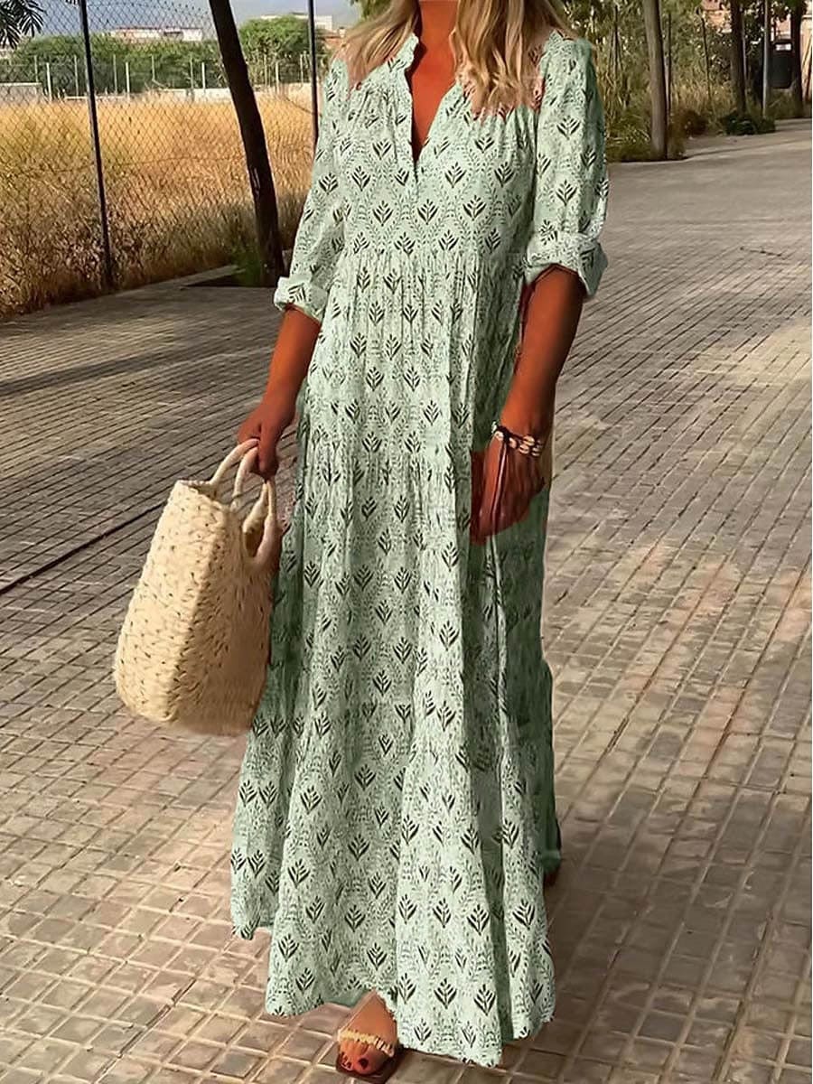 Model in a flowing boho maxi dress on a clean sidewalk background.