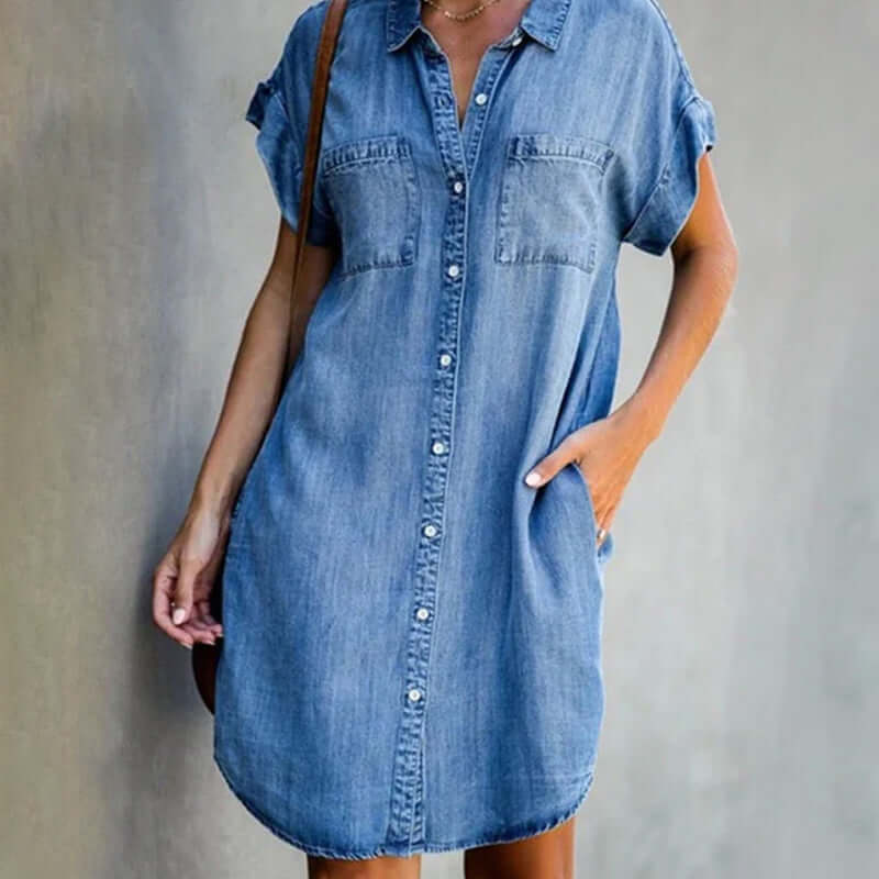 Woman wearing a short sleeve denim shirt dress on a plain background.