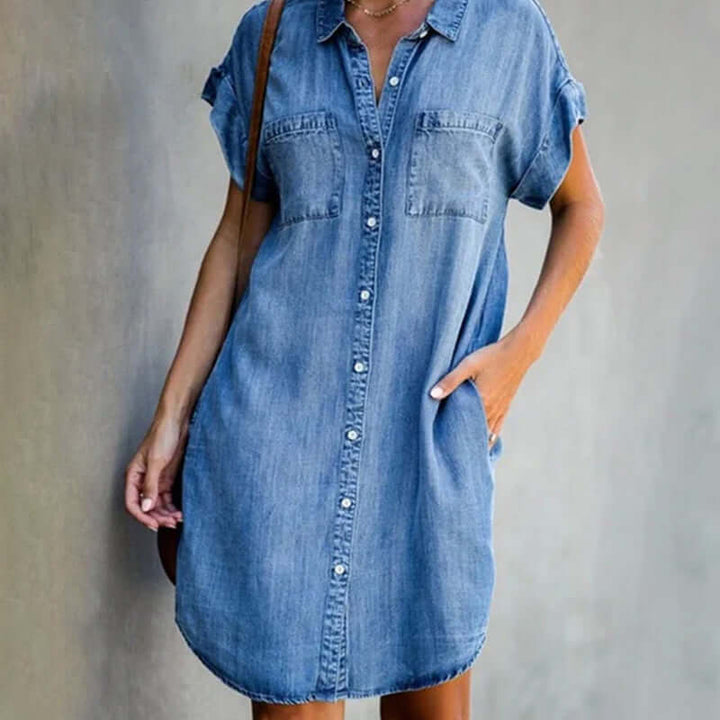 Woman wearing a short sleeve denim shirt dress on a plain background.
