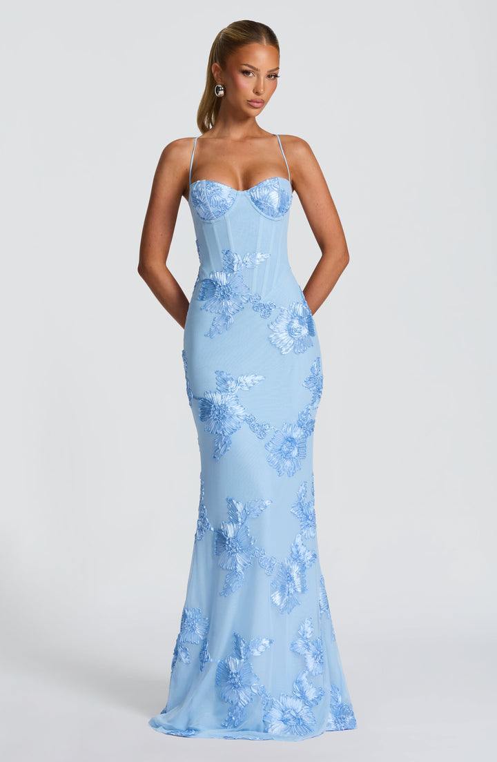 Female model displaying floral evening dress front angle plain background.