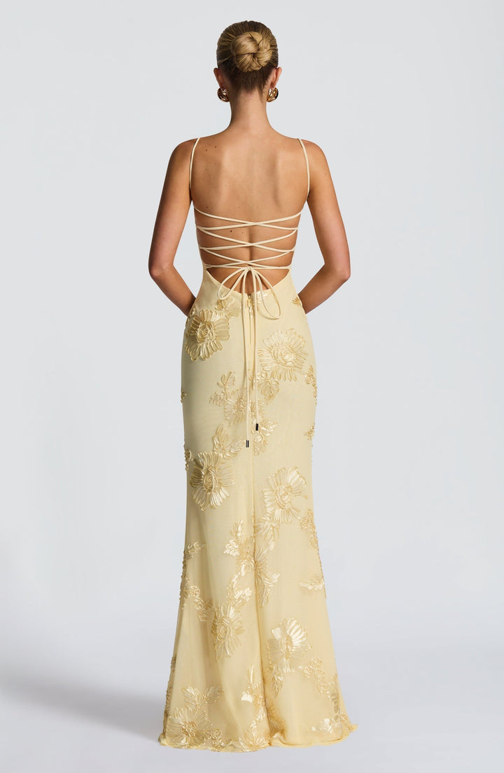 Woman showing fitted embroidered dress full length on plain background, back view