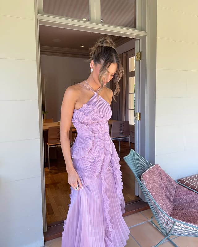 Female model showing flowing silhouette of formal dress indoors beautifully.