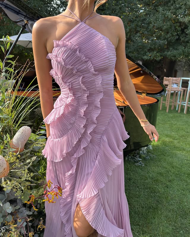 Woman in sophisticated maxi dress standing in outdoor ambiance.