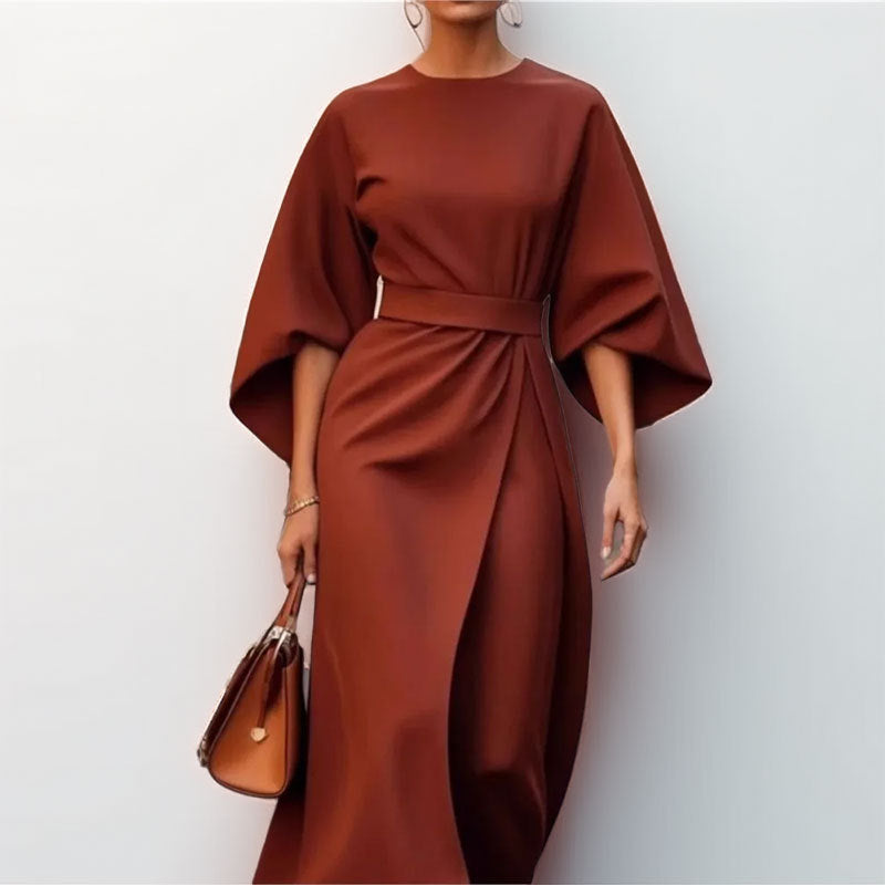 Woman wearing a satin batwing maxi dress with a draped silhouette on a plain background.