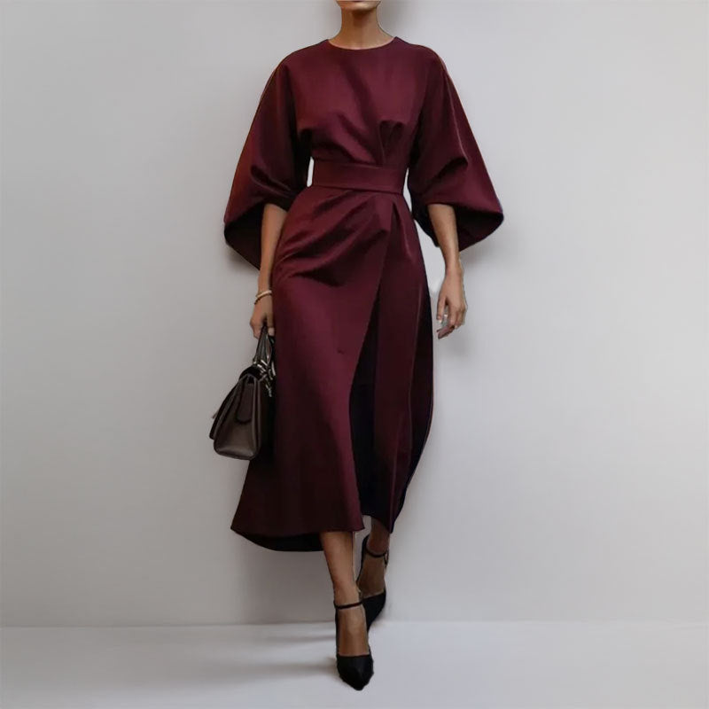 Model wearing a draped satin maxi dress with a fitted waist on a plain background.