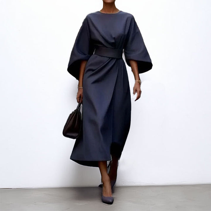 Female styled in a draped evening maxi dress with a fitted waist on a clean background.