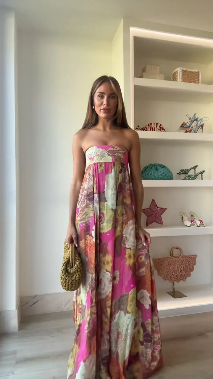 Woman wearing elegant summer floral maxi dress against plain cabinet background