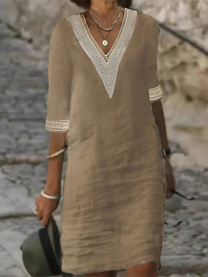 Female in a summer midi dress with lace trim standing against a rustic stone wall.
