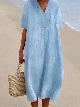 Woman wearing a V-neck relaxed midi dress against a plain background.
