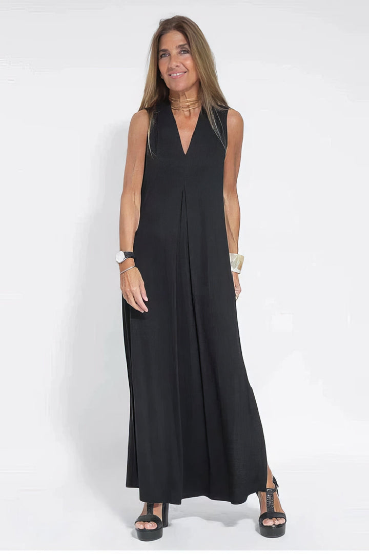 Elegant long dress w/ model on a plain background, showing a soft flowing silhouette.